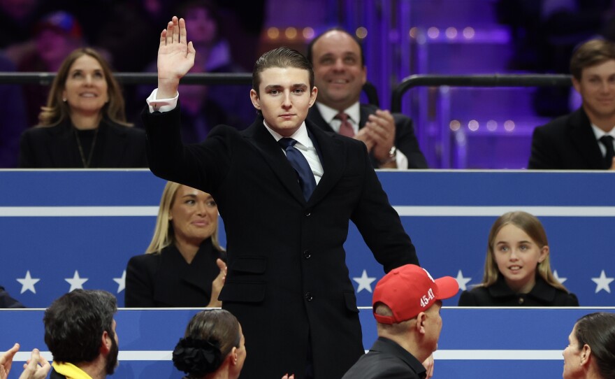 Barron Trump waves to the crowd during an indoor inauguration parade at Capital One Arena.