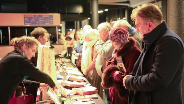 2025年12月18日，觀眾在阿姆內維爾大劇院（Galaxie Amnéville）內購買神韻商品和《轉法輪》等書籍。（圖片來源：章樂／大紀元）