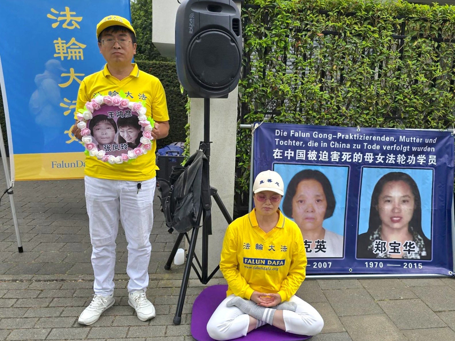 圖16:法輪功學員手持受因修煉法輪功遭受中共迫害致死的親人照片。(明慧網)